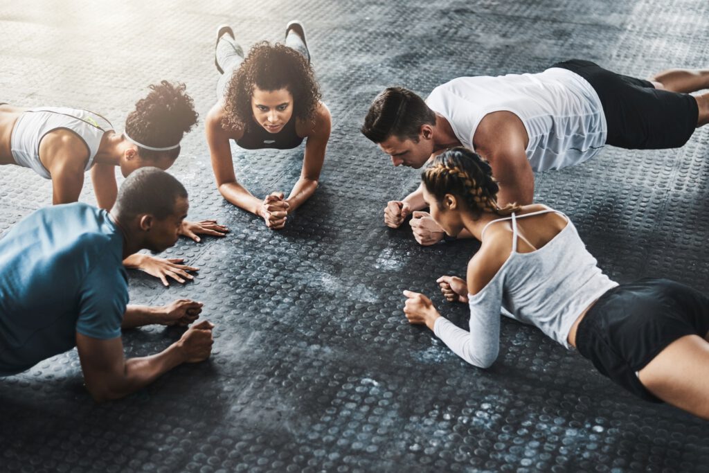 Shot of a group of young people doing planks together during their workout in a gym
