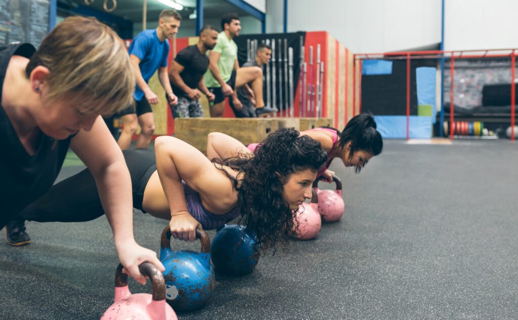 Sportswomen doing push-ups with kettlebells